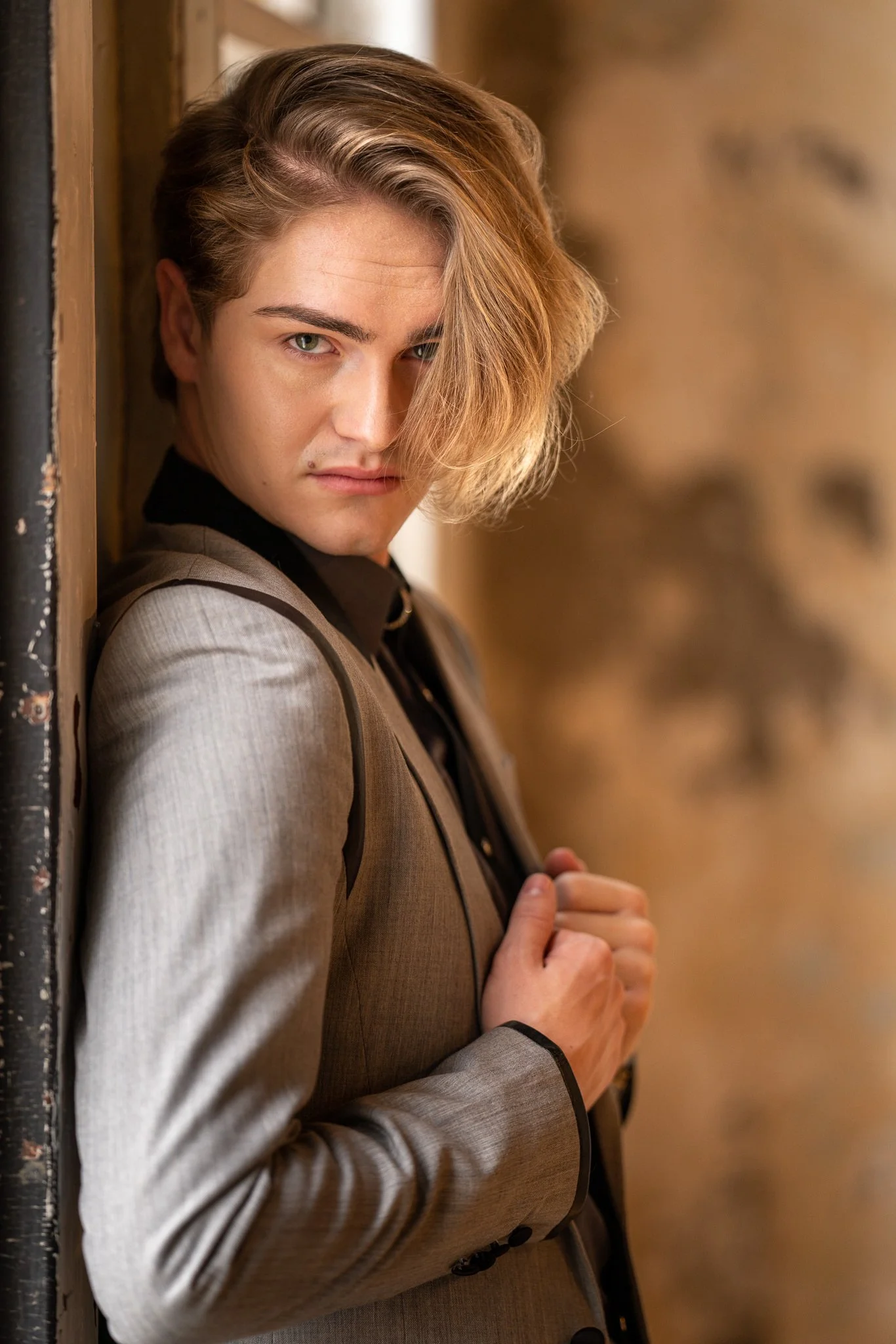 A young man in a grey jacket leaning in a doorway