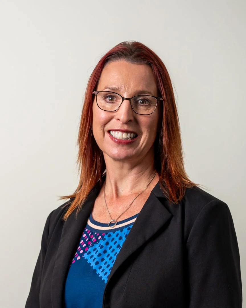A smiling corporate headshot of a woman with red hair