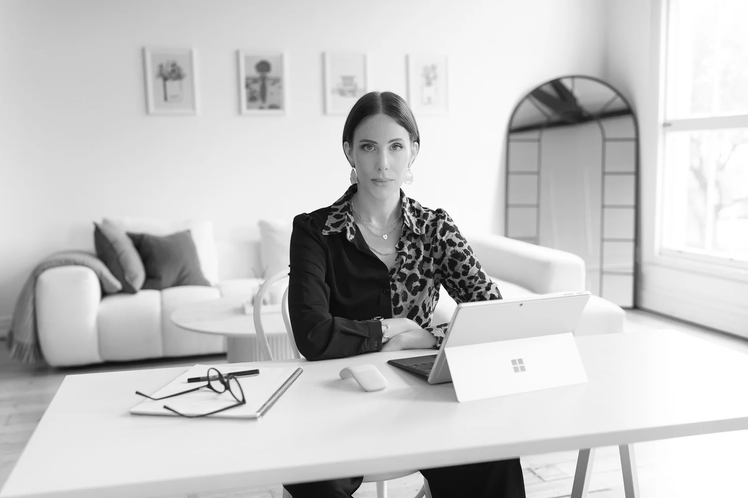 Black and white photo of a businesswoman working at a white desk