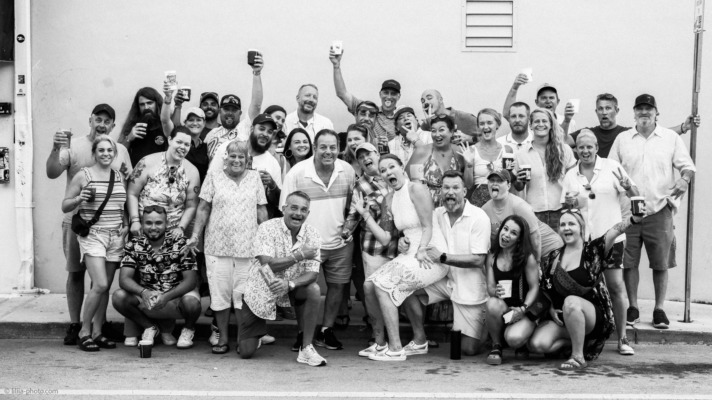 Group of people gathered outside, smiling and celebrating, holding cups.