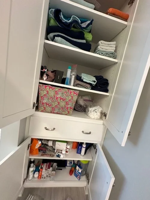 Open bathroom closet filled with towels, toiletries, and personal care items.