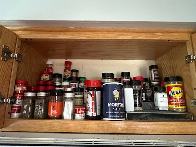 An open kitchen cabinet containing various spice jars and containers, including Morton Salt and Wundo spice blend.