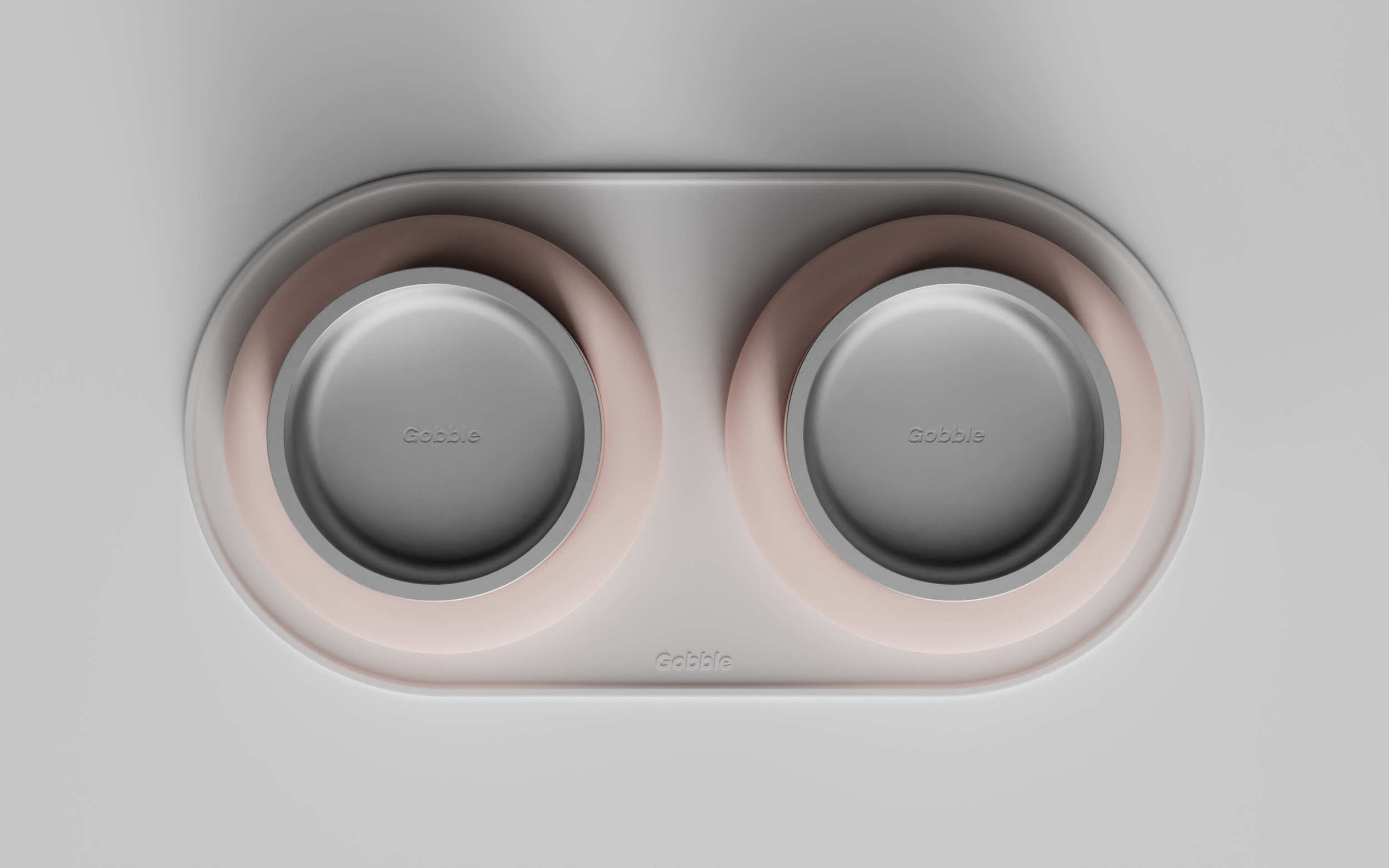 Close-up of a modern dog bowl on a silicone pad, with pink silicone rings around the bowls to stop them sliding "Gobble" branding, embedded in the bowl.