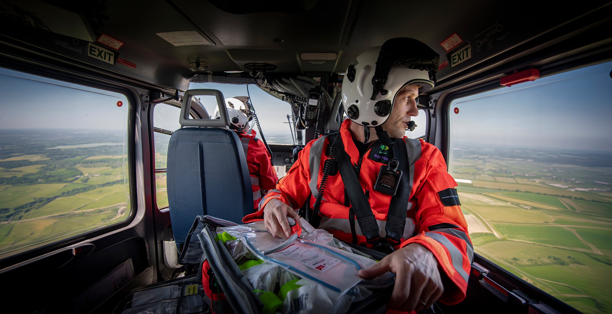 Air Ambulance doctor wearing a helmet looking out of helicopter window.