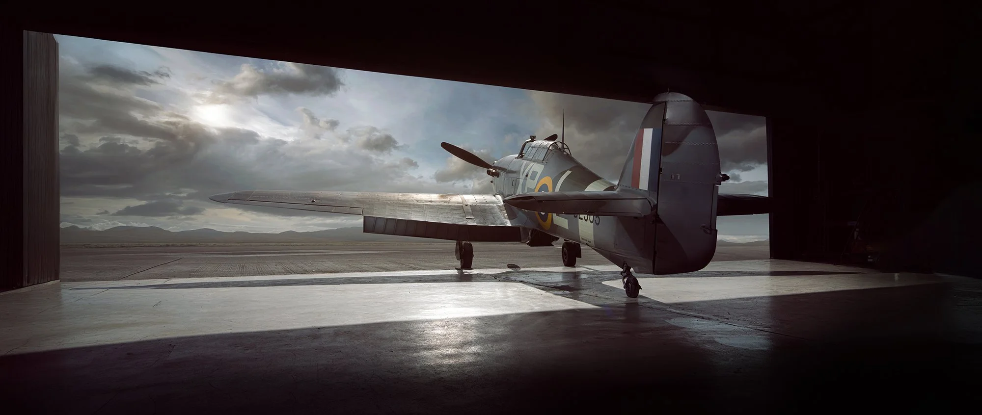 Hawker Hurricane aircraft in hanger doorway at sunset.