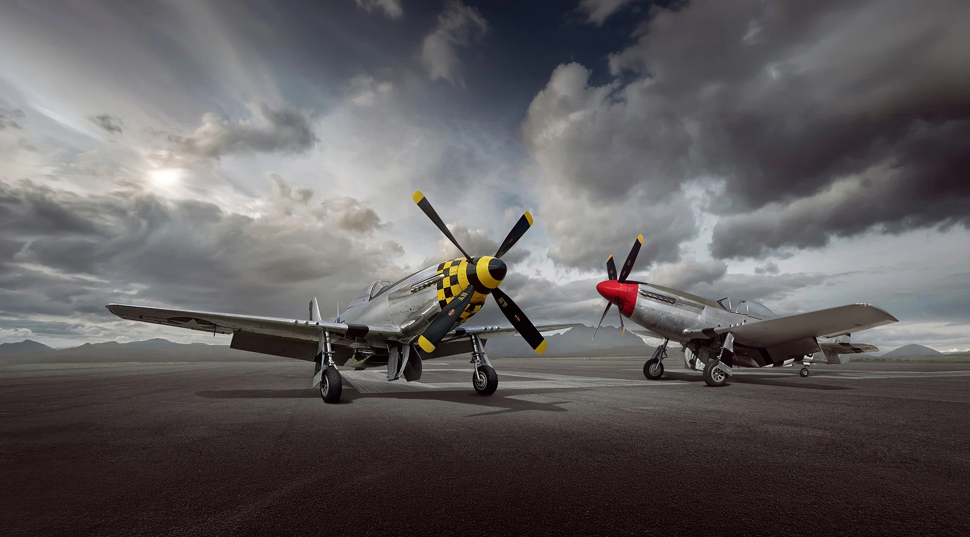 2 P51 Mustangs on a runway with cloudy skies overhead.