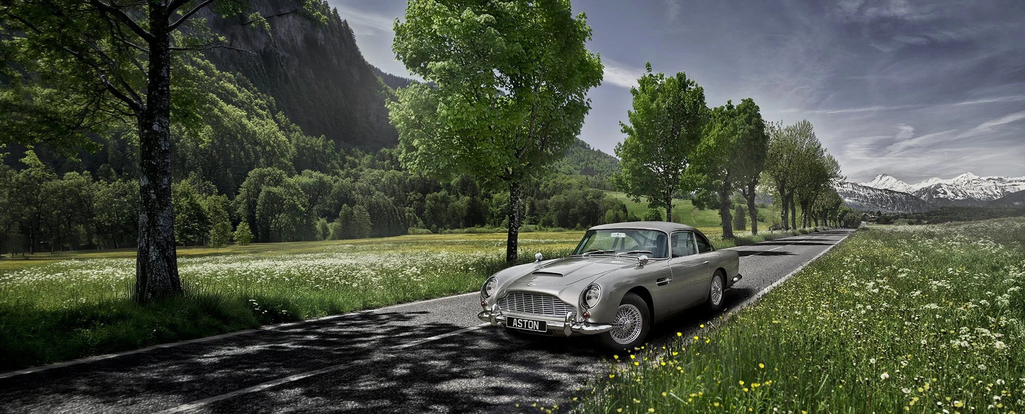 Aston Martin DB5 on road with Swiss Alps in background, car photography.