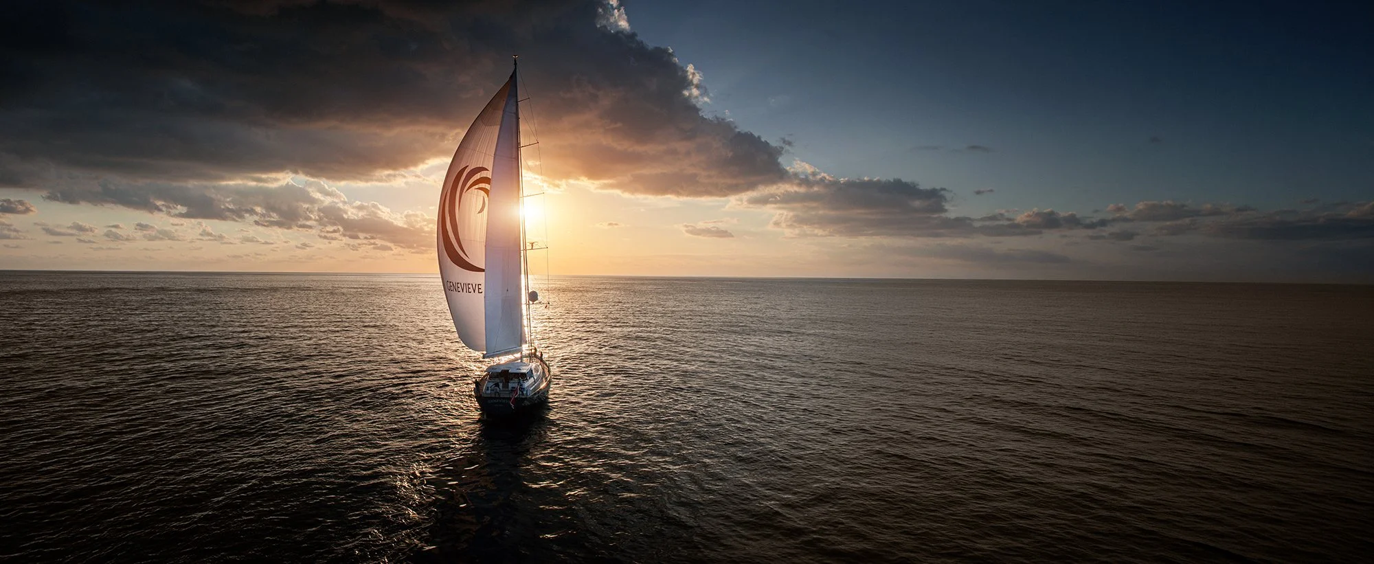 Yacht sailing into sunset at sea