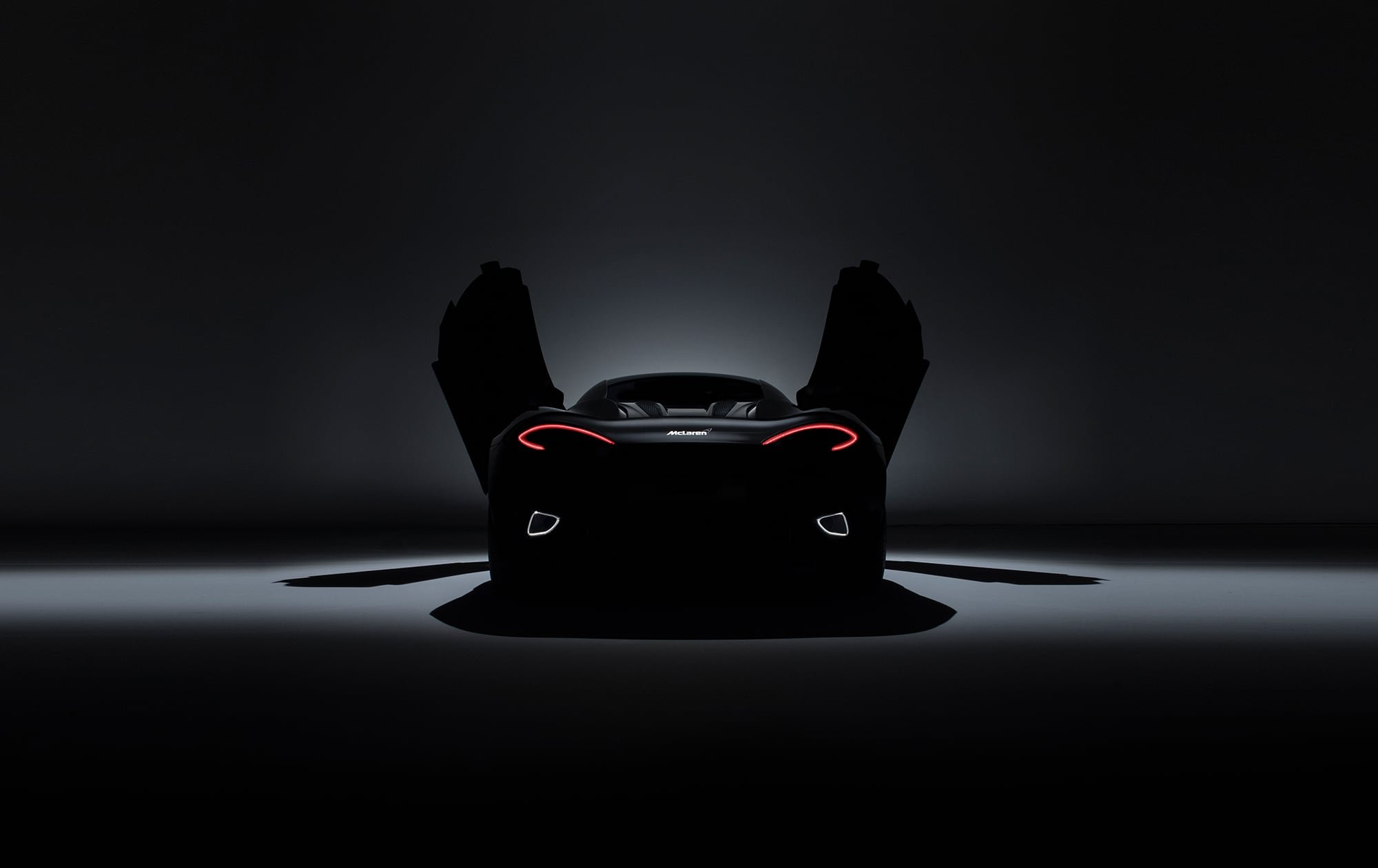 Rear view of McLaren supercar in studio as a silhouette