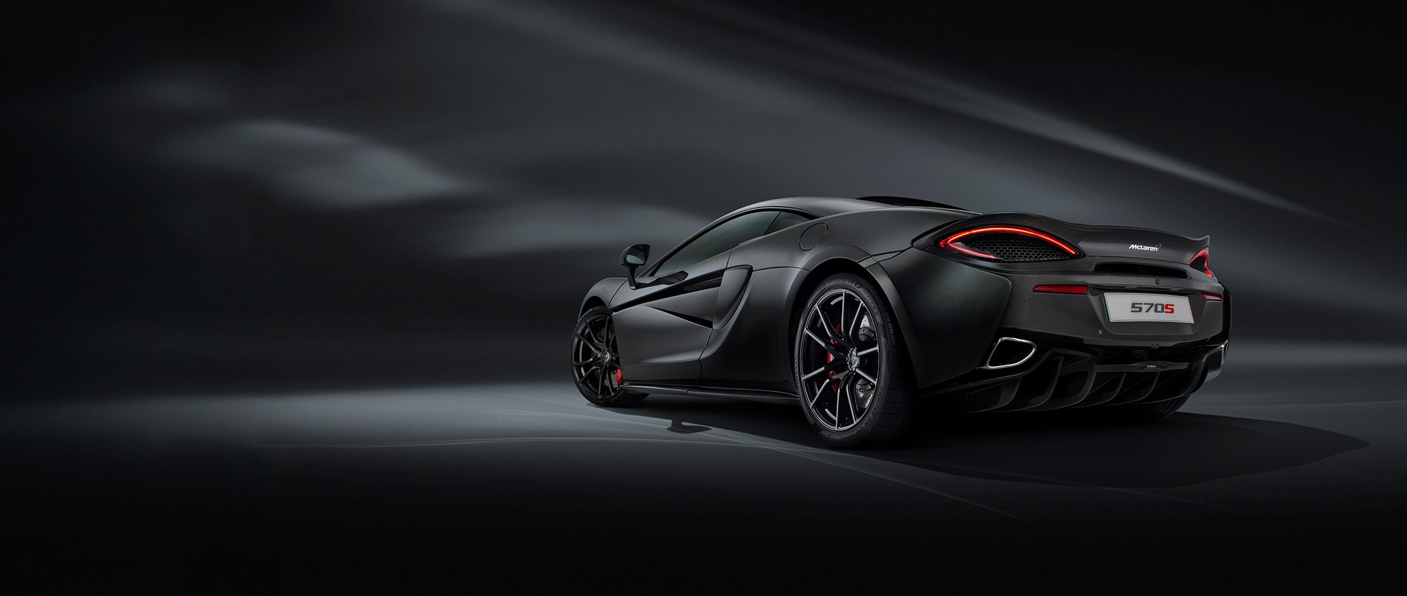 McLaren 570s car, rear view, in a dark studio setting.