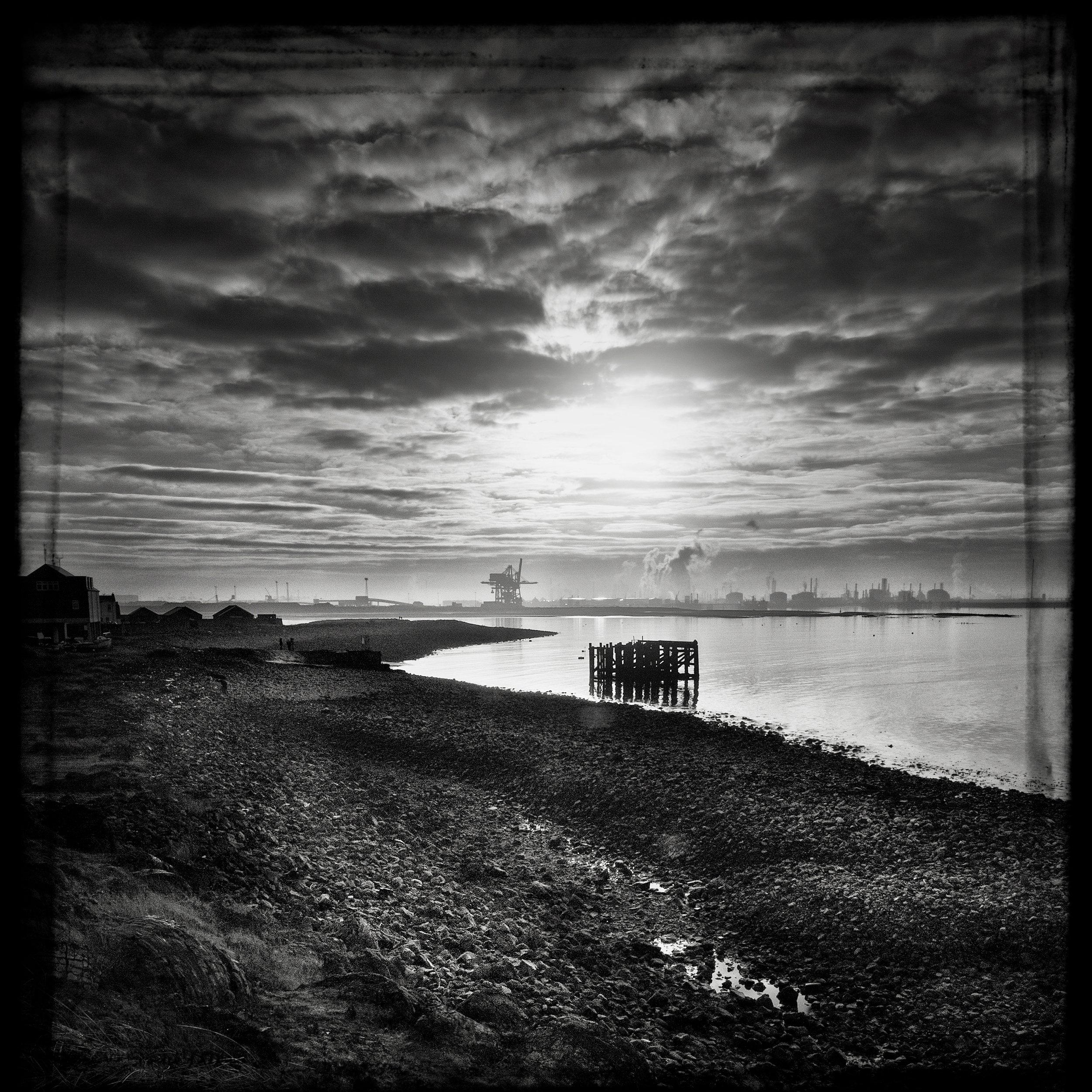 Black and white photograph, Redcar with industry in background on coast.