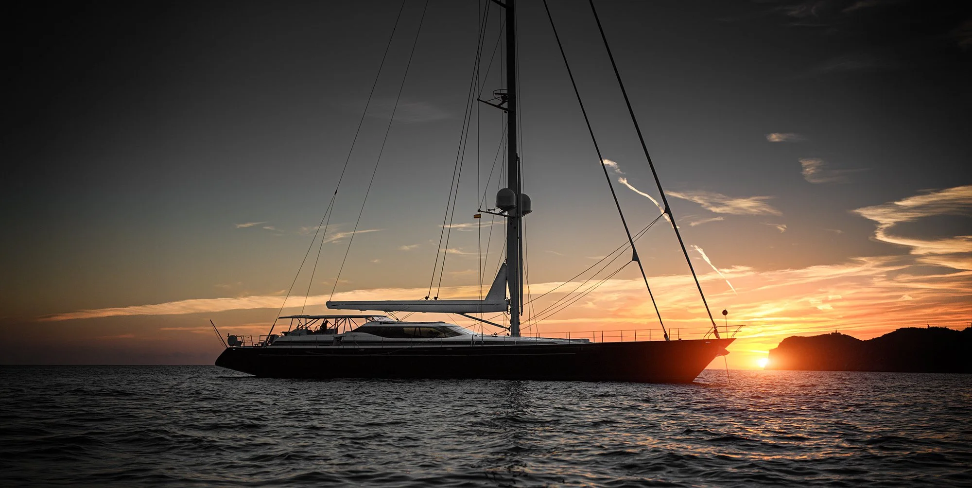 Yacht anchored with sun setting in distance.