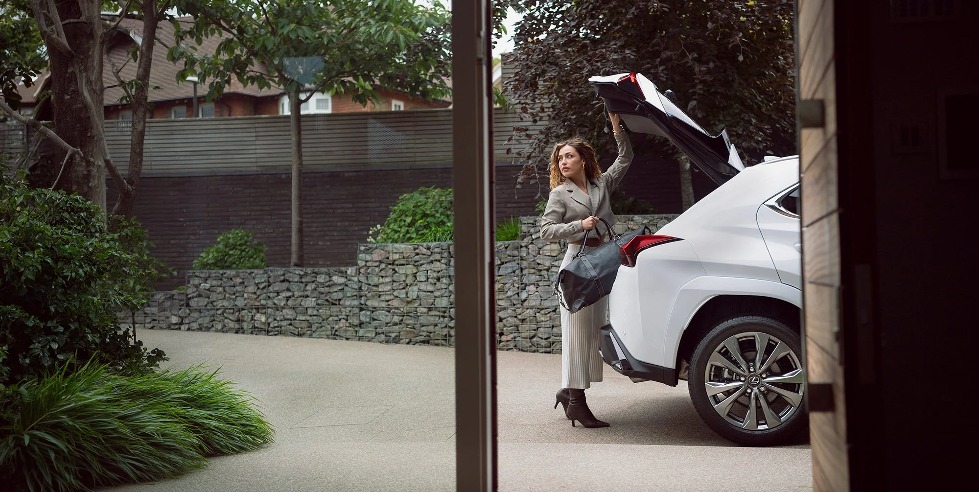 Woman opening boot of white Lexus car.