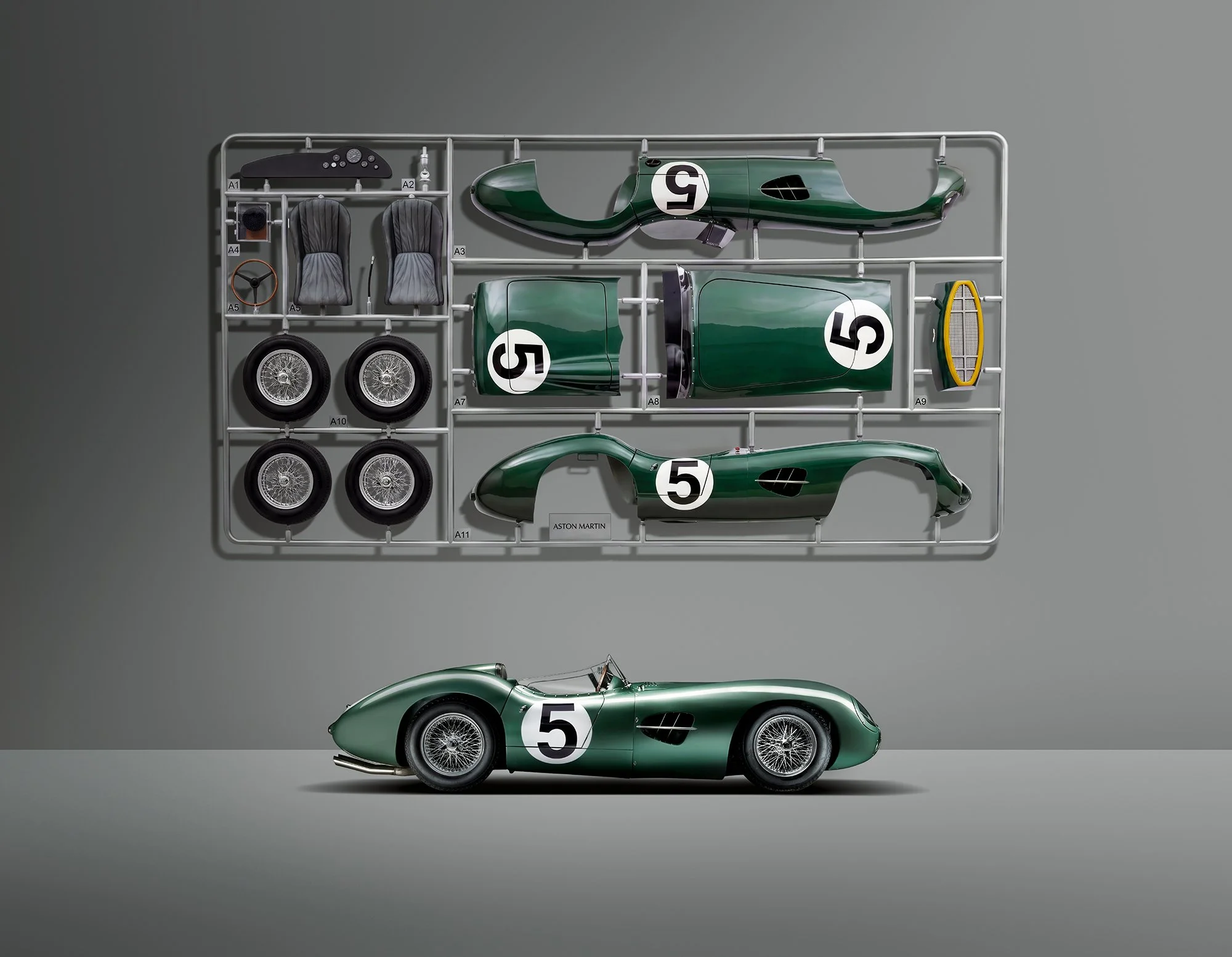 Aston Martin DBR1 with model kit on wall behind.