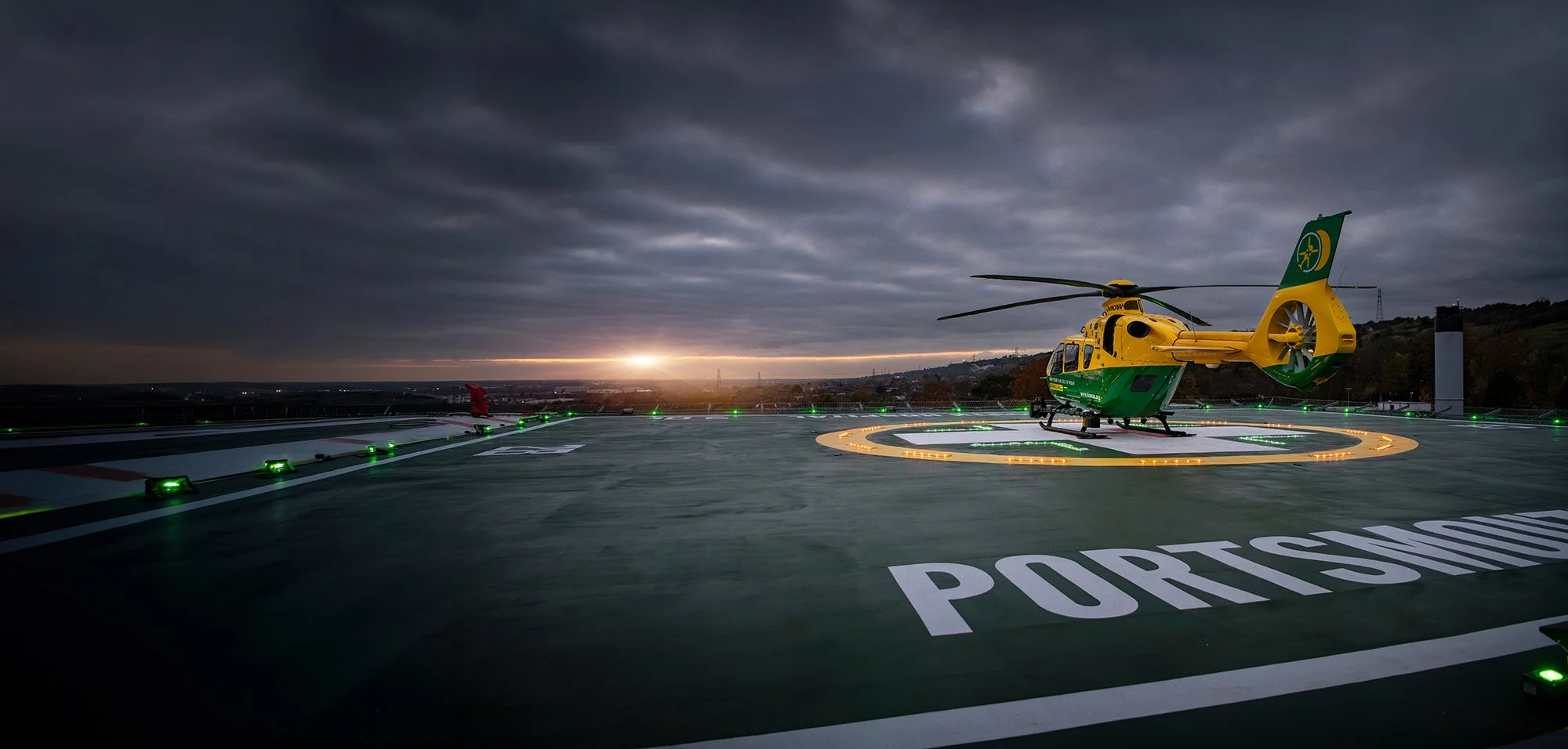 Air Ambulance helicopter at sunset on landing pad of hospital.