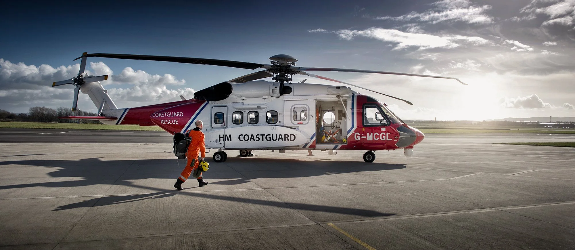 HM Coastguard Helicopter with SAR pilot walking towards ready to take off.