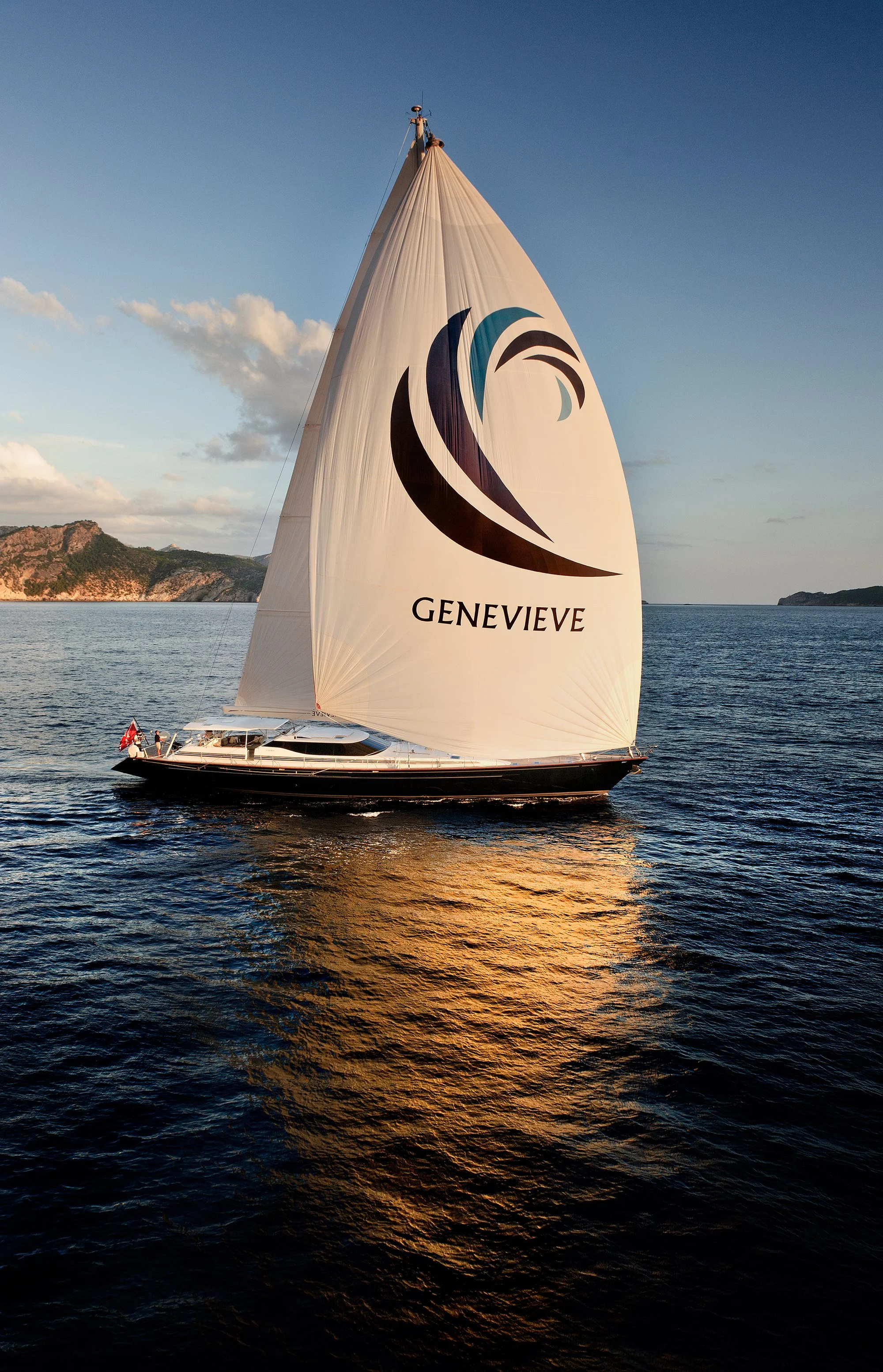 Luxury super yacht sailing across open water  with reflection of sail in water. 