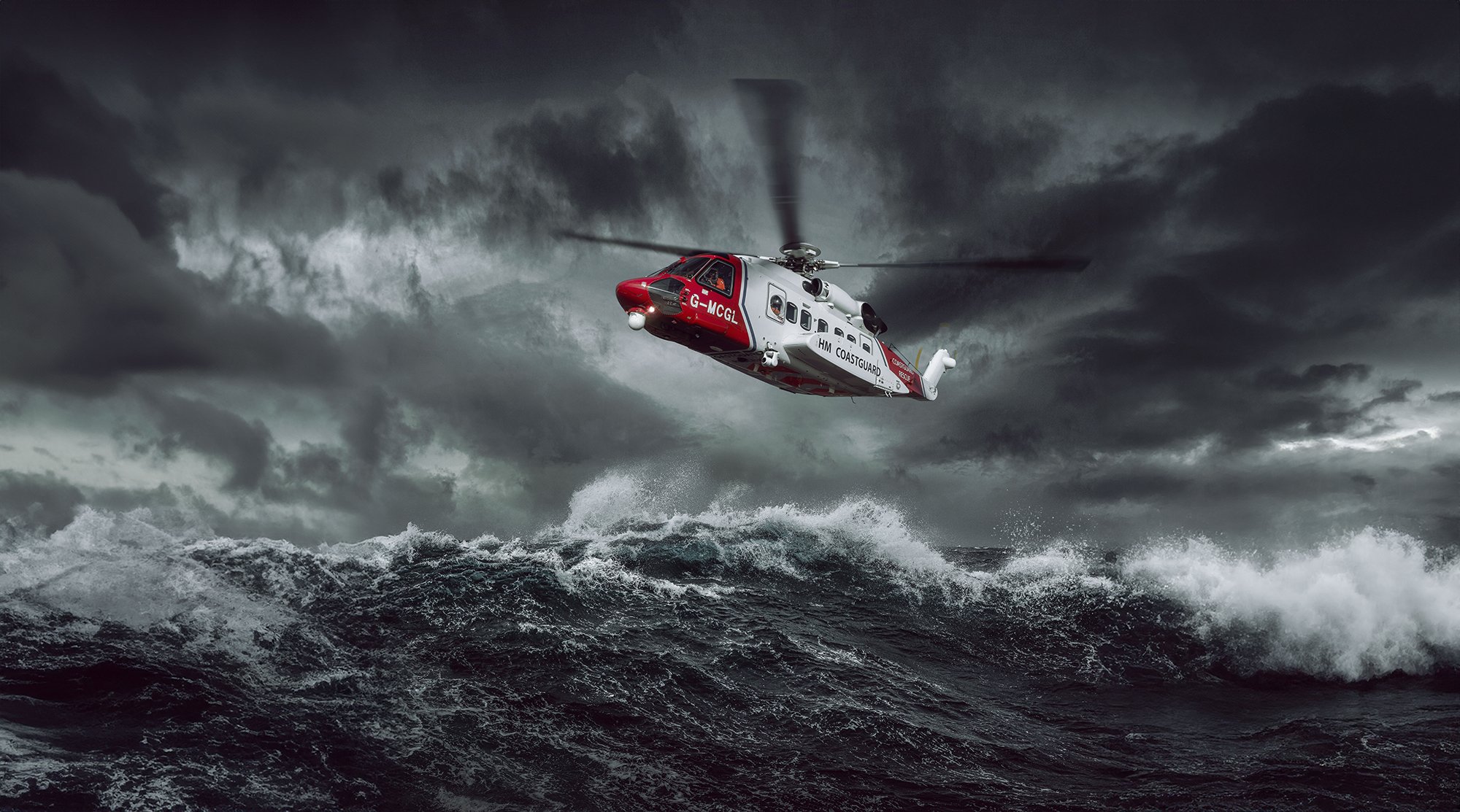 HM Coastguard Helicopter hovering over rough seas, aviation photography.