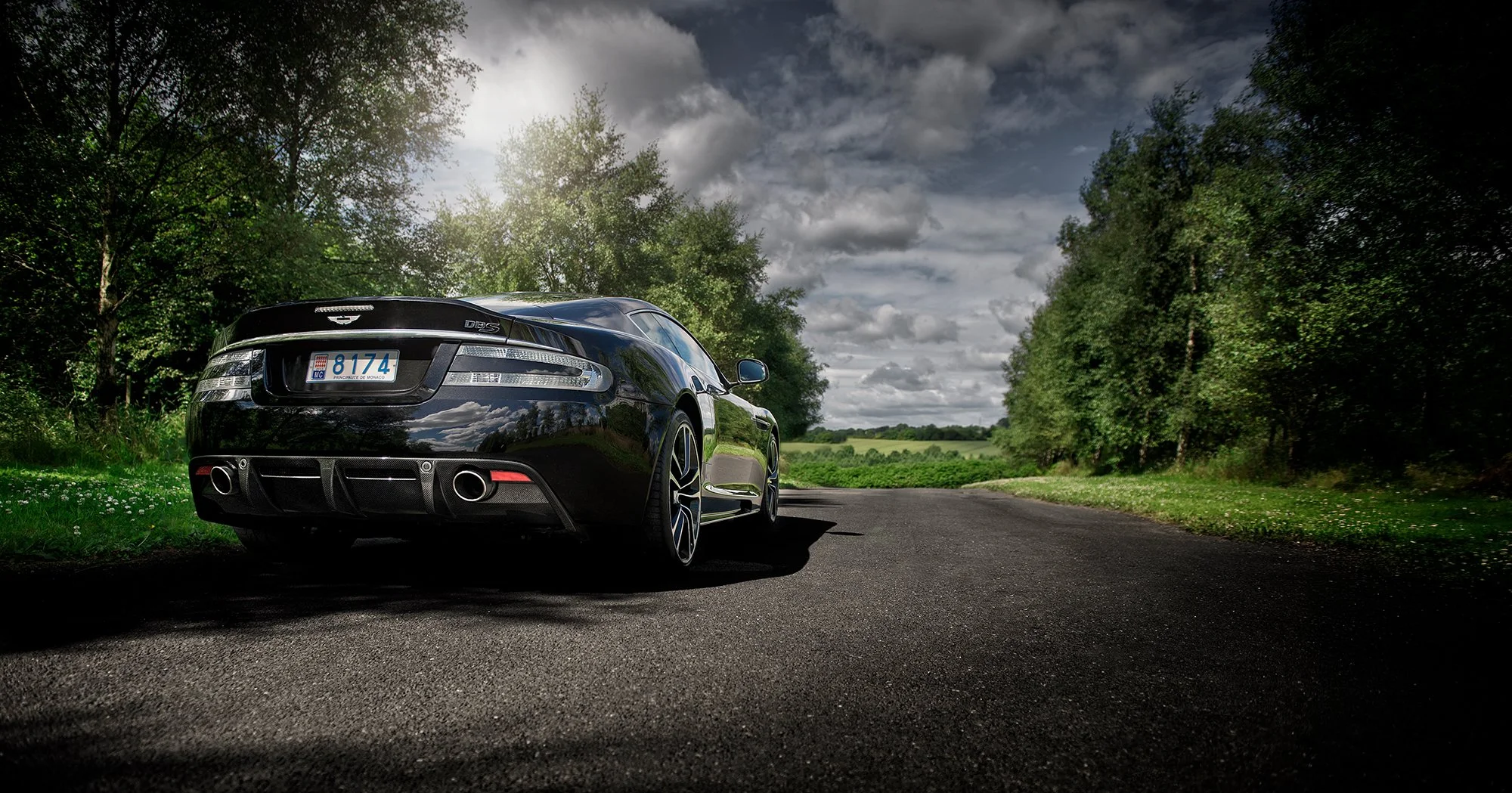 Aston Martin DBS rear view on country road.