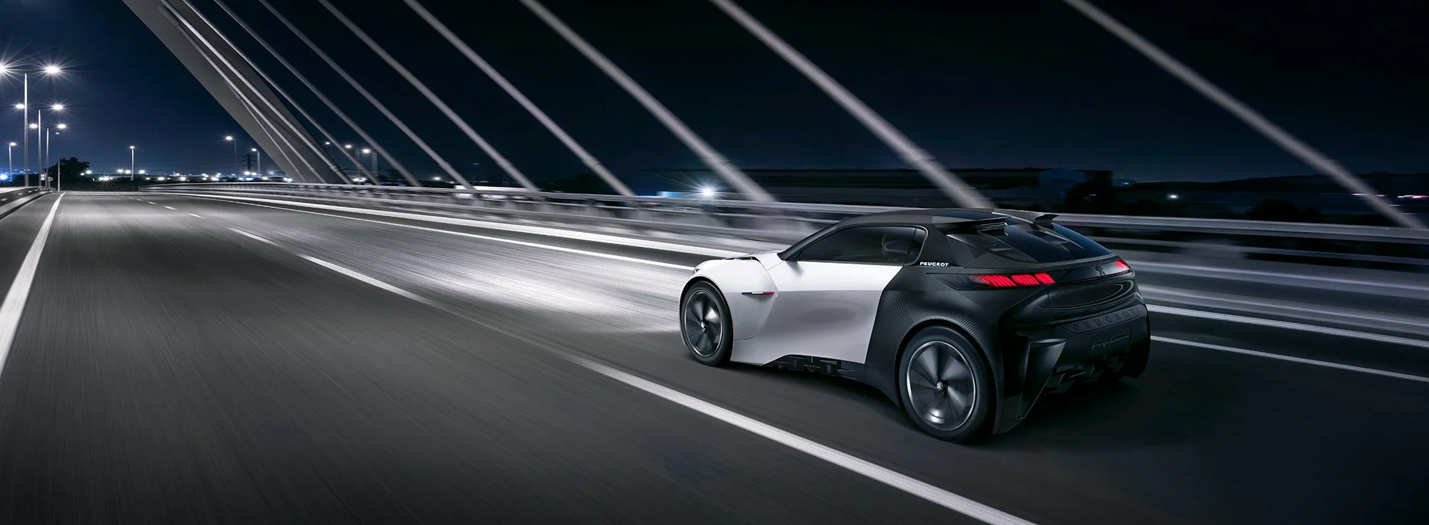 Concept car driving across bridge at night.