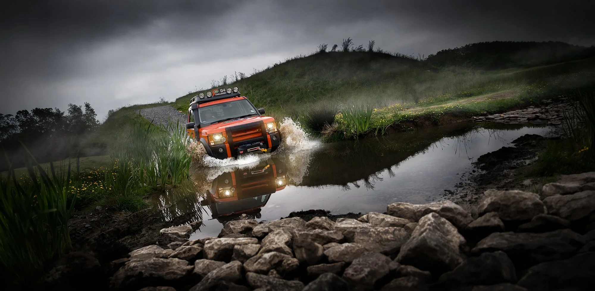 Land Rover Defender driving through river.