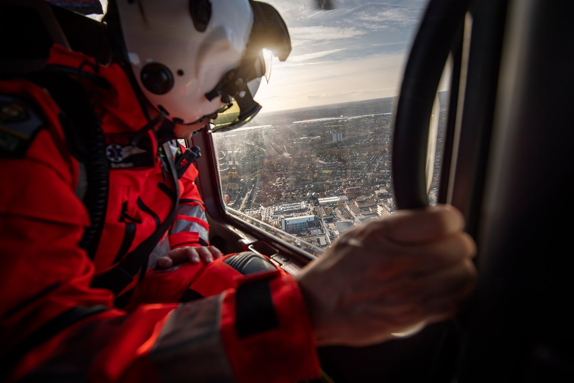 Air Ambulance doctor in helicopter in flight wearing helmet and flight suit. 