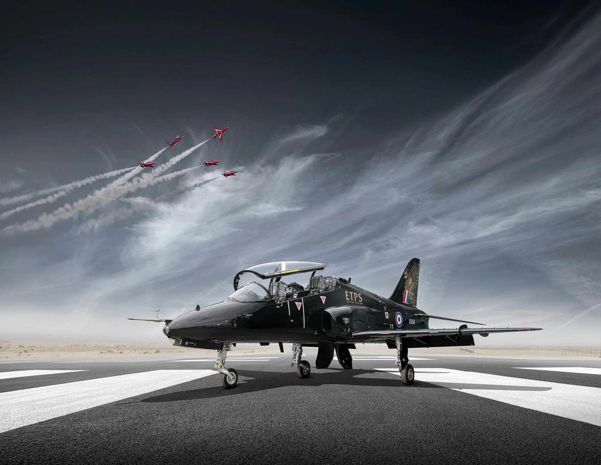 Hawk T1 jet on runway with red arrows flying in distance. 