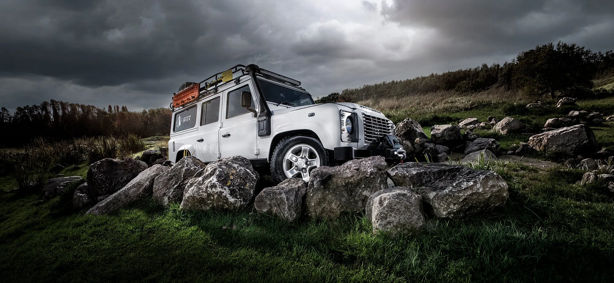Land Rover Defender driving across large rocks.