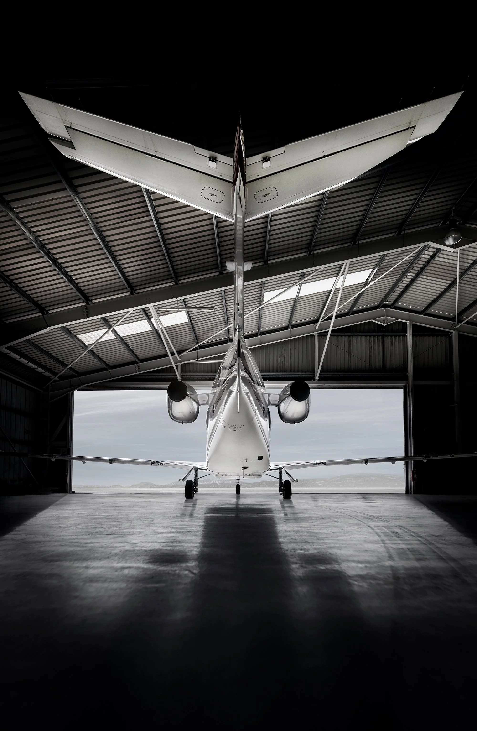 Rear of private jet in hanger with hanger doors open, aviation photography.