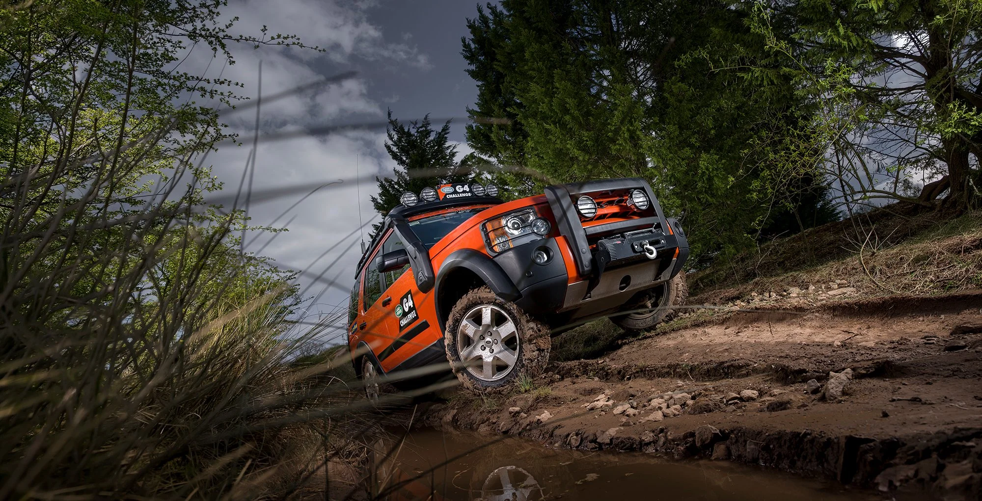 Land Rover Defender on muddy dirt track.