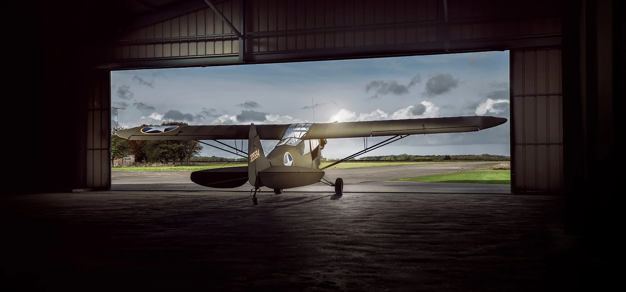 Aviation Photography of a WW2 aircraft sat at the doors of a hanger