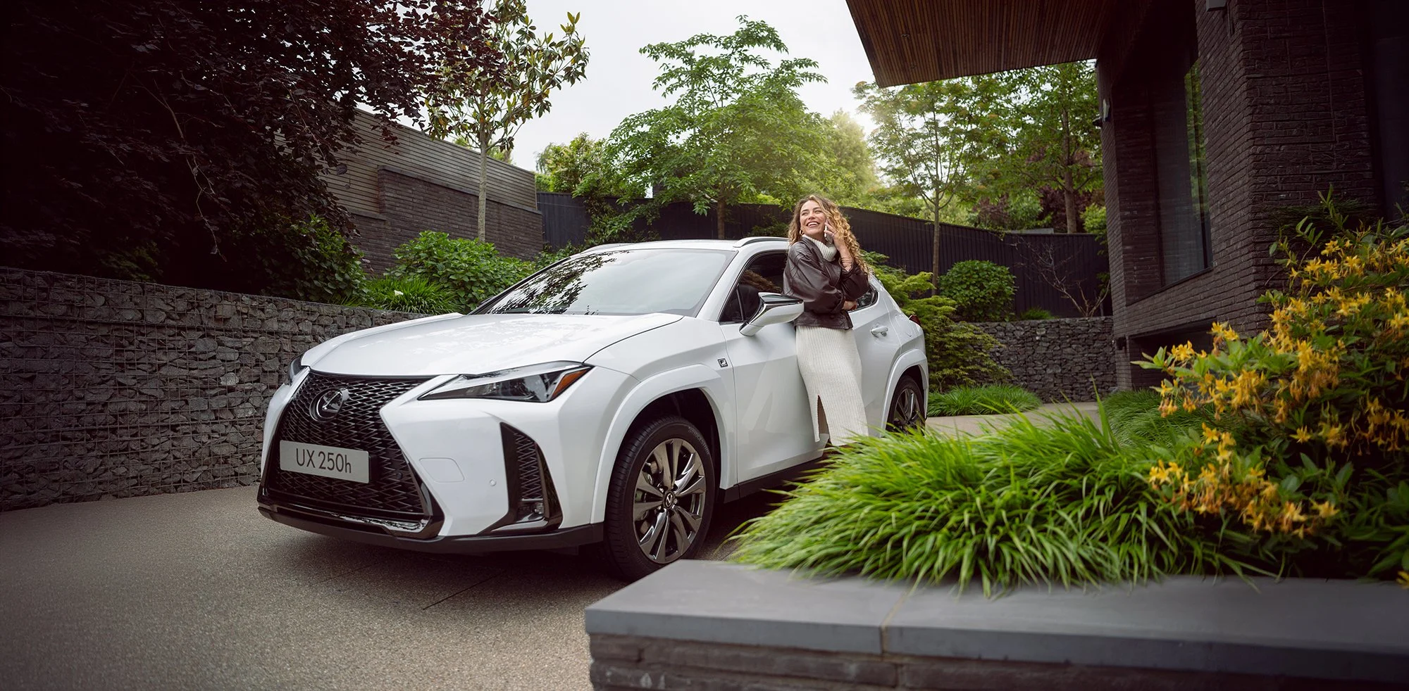 Woman on phone stood next to white Lexus car.
