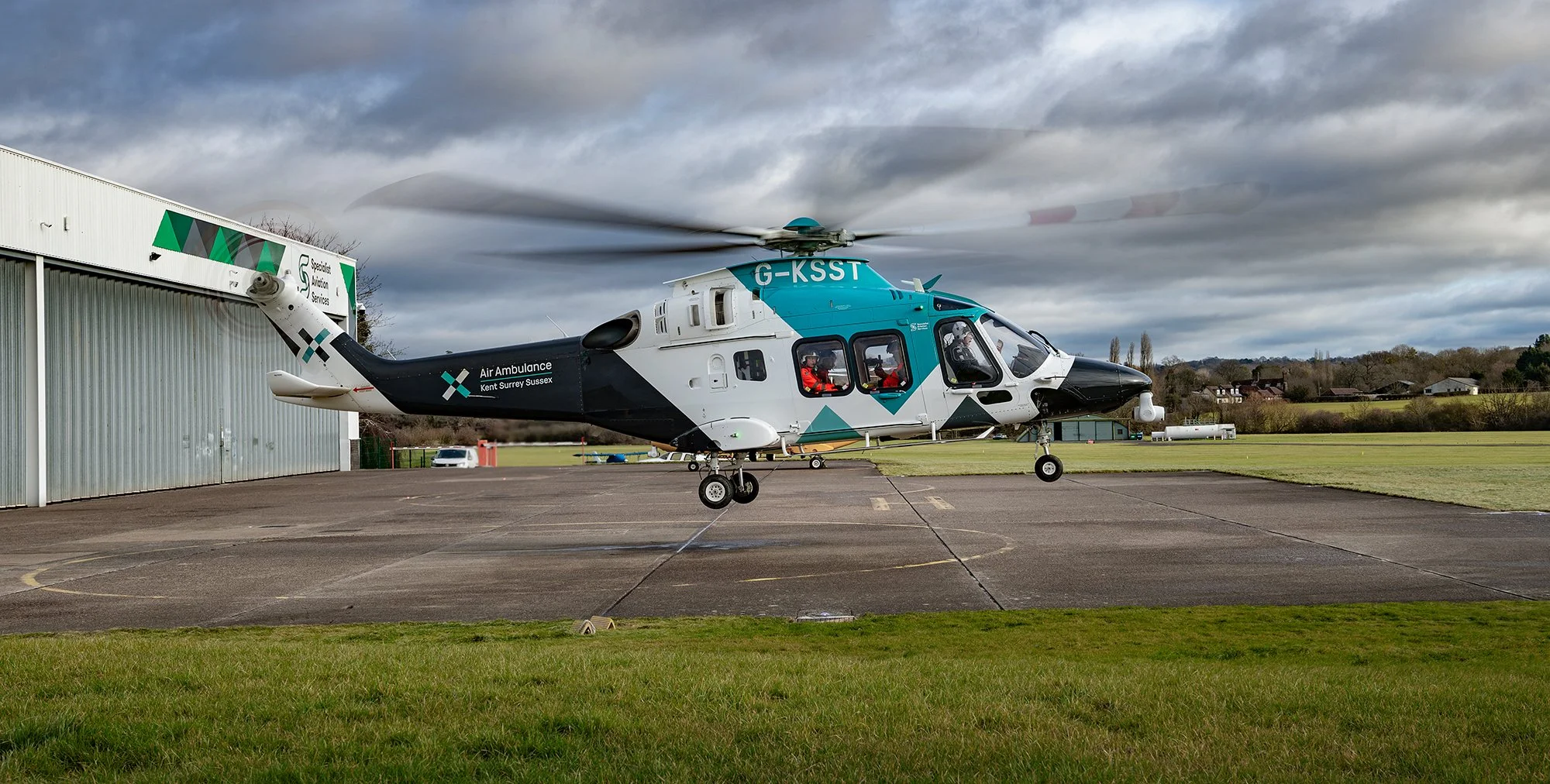 Kent Air Ambulance helicopter taking off, side view.