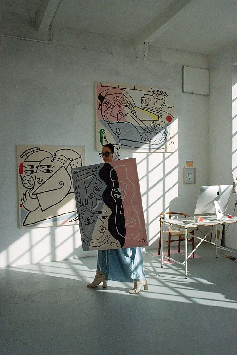 Kristina Supernova carrying her painting across the studio
