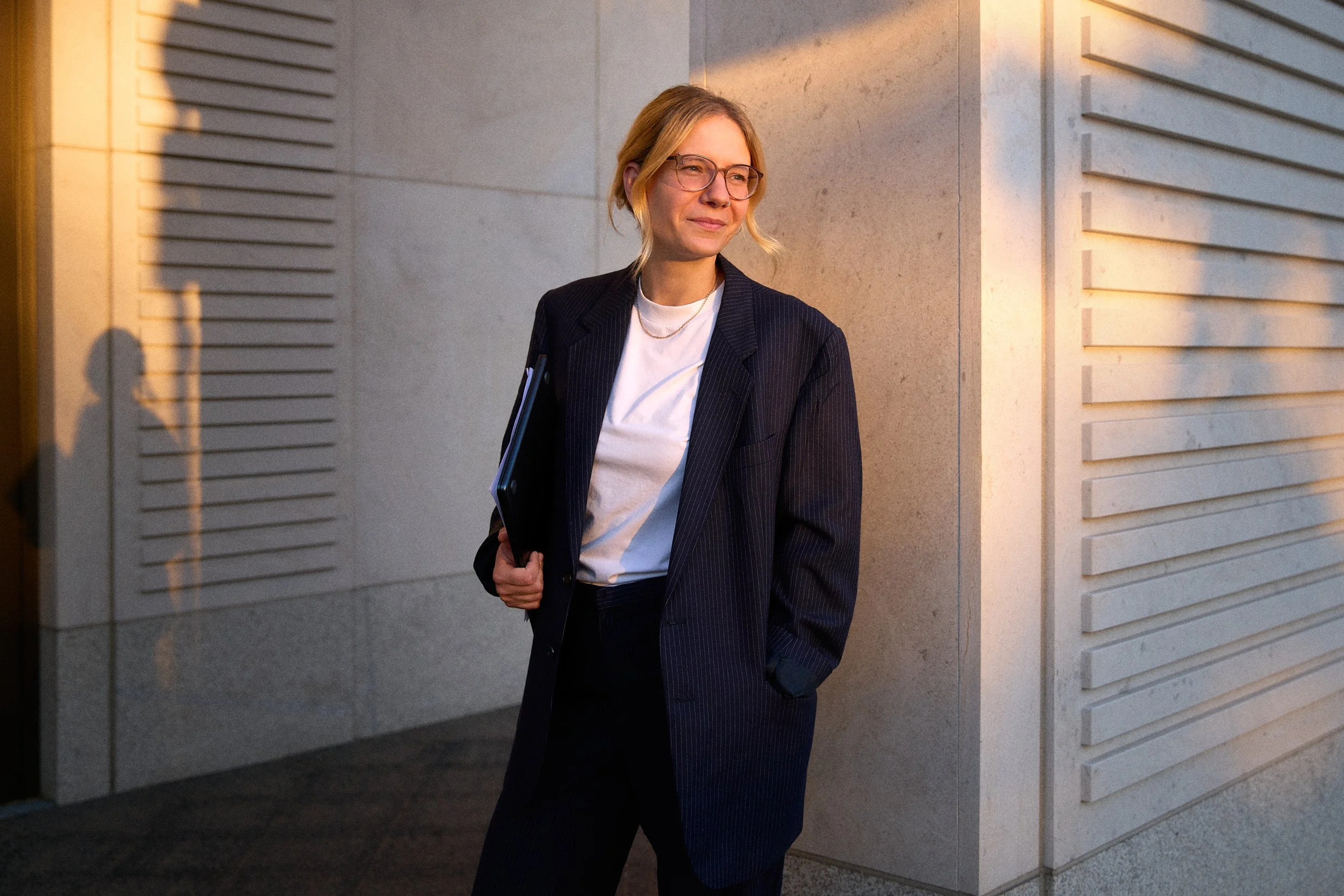 Young female lawyer smiling wearing a suit in warm atmospheric lightning business portrait photographed by Tereza Konarikova in Berlin