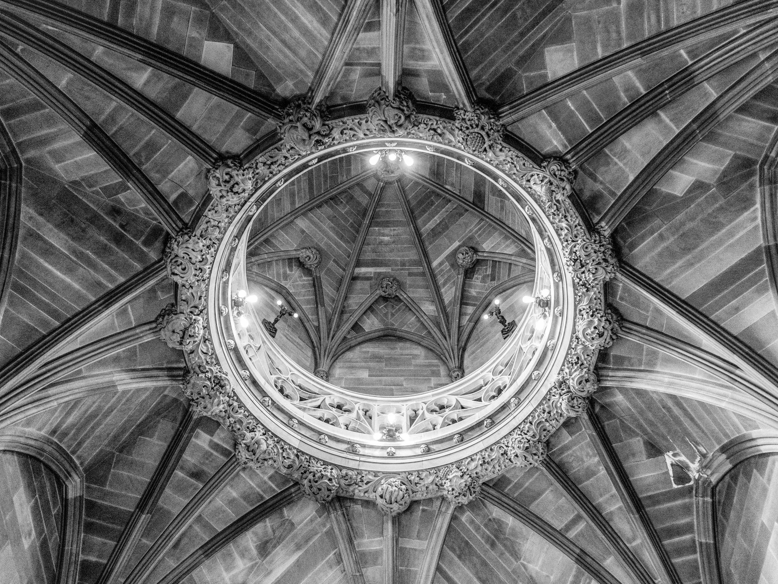 A black and white image of an ornate, vaulted ceiling with intricate architectural details.