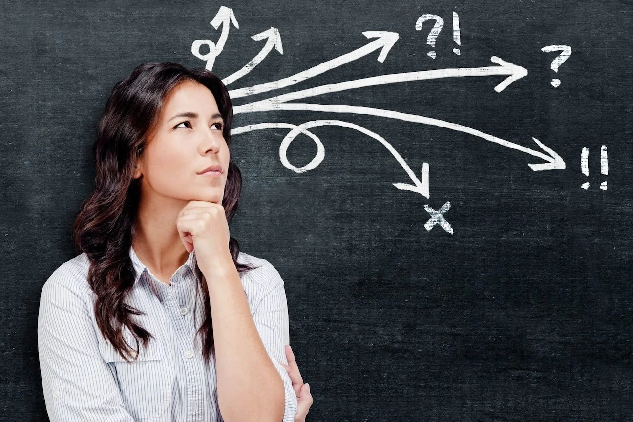 woman pondering in front of a black background and white arrows and symbols
