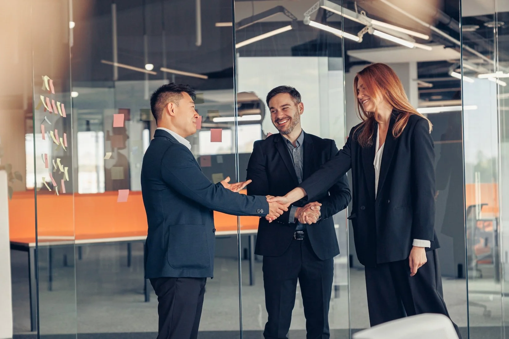 A Business Executive and Two Private Equity Partners Shaking hands in an office setting.