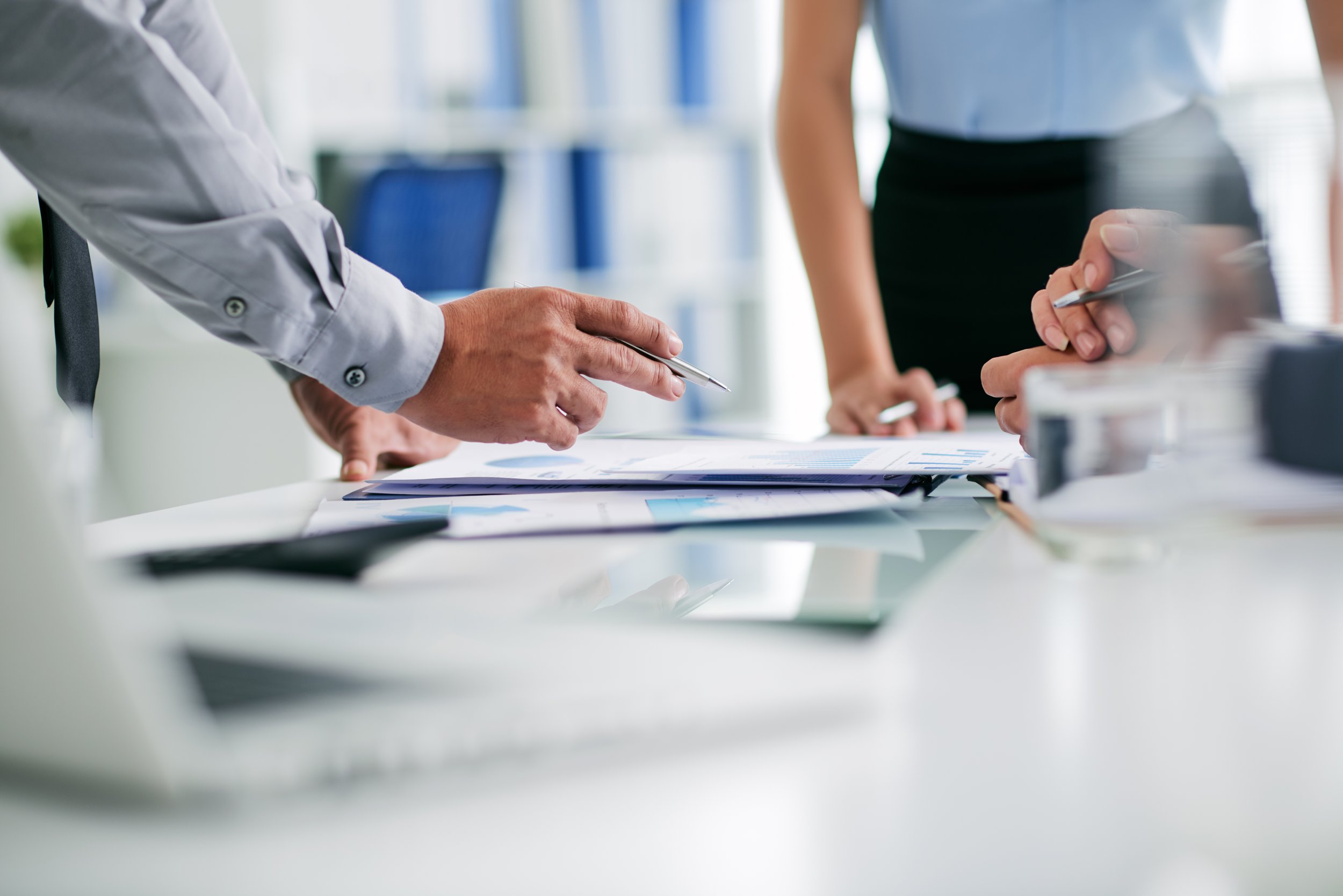 Leaders outlining a business strategy for growth with executive's hands pointing at charts on the table
