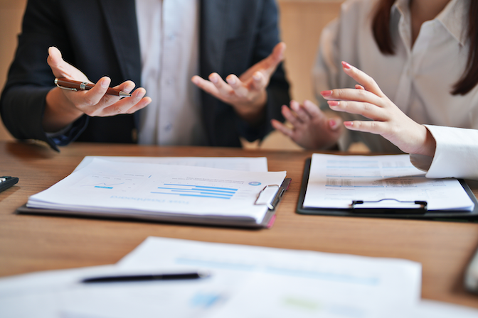 Two business people sitting at a table with business documents about creating another business entity