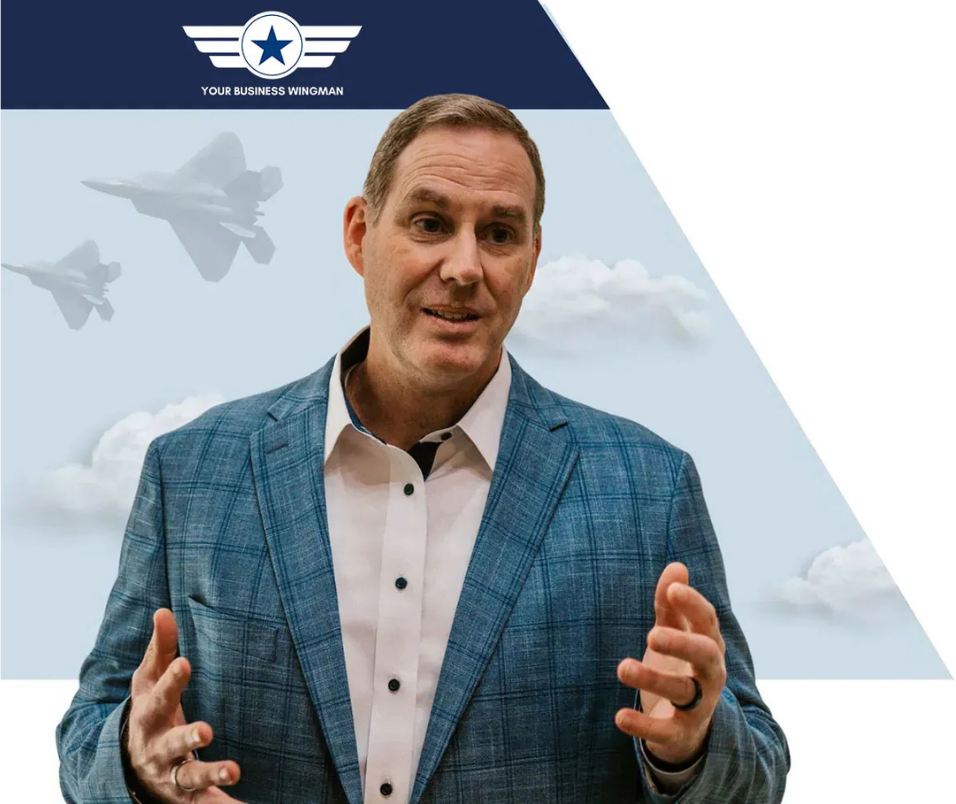 A man in a blue checkered blazer and white shirt speaking in front of a background with fighter jets and clouds, with a logo at the top that features a star and wings and the text "Your Business Wingman."