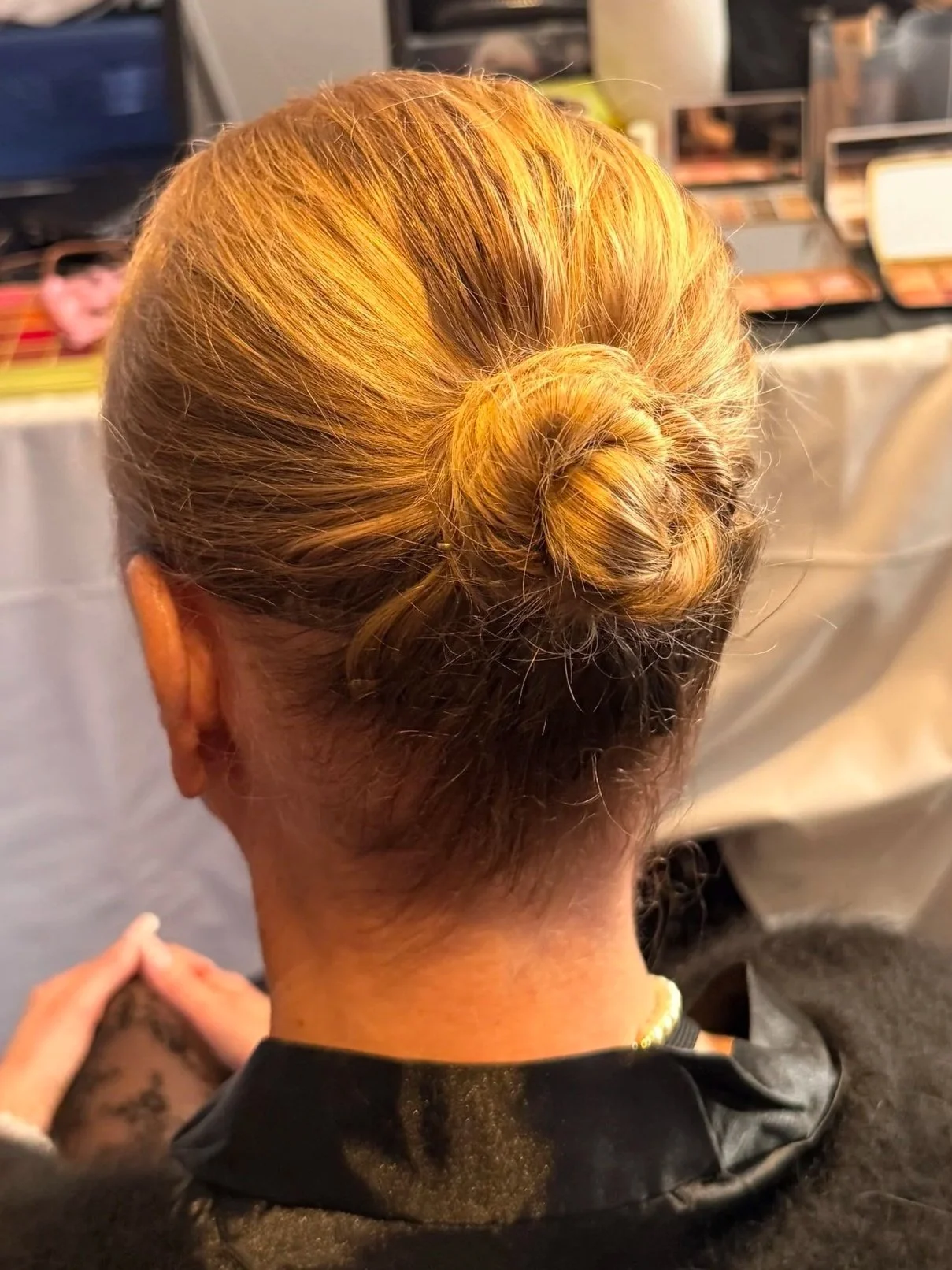 Back view of a person's head with blonde hair styled in a neat bun.
