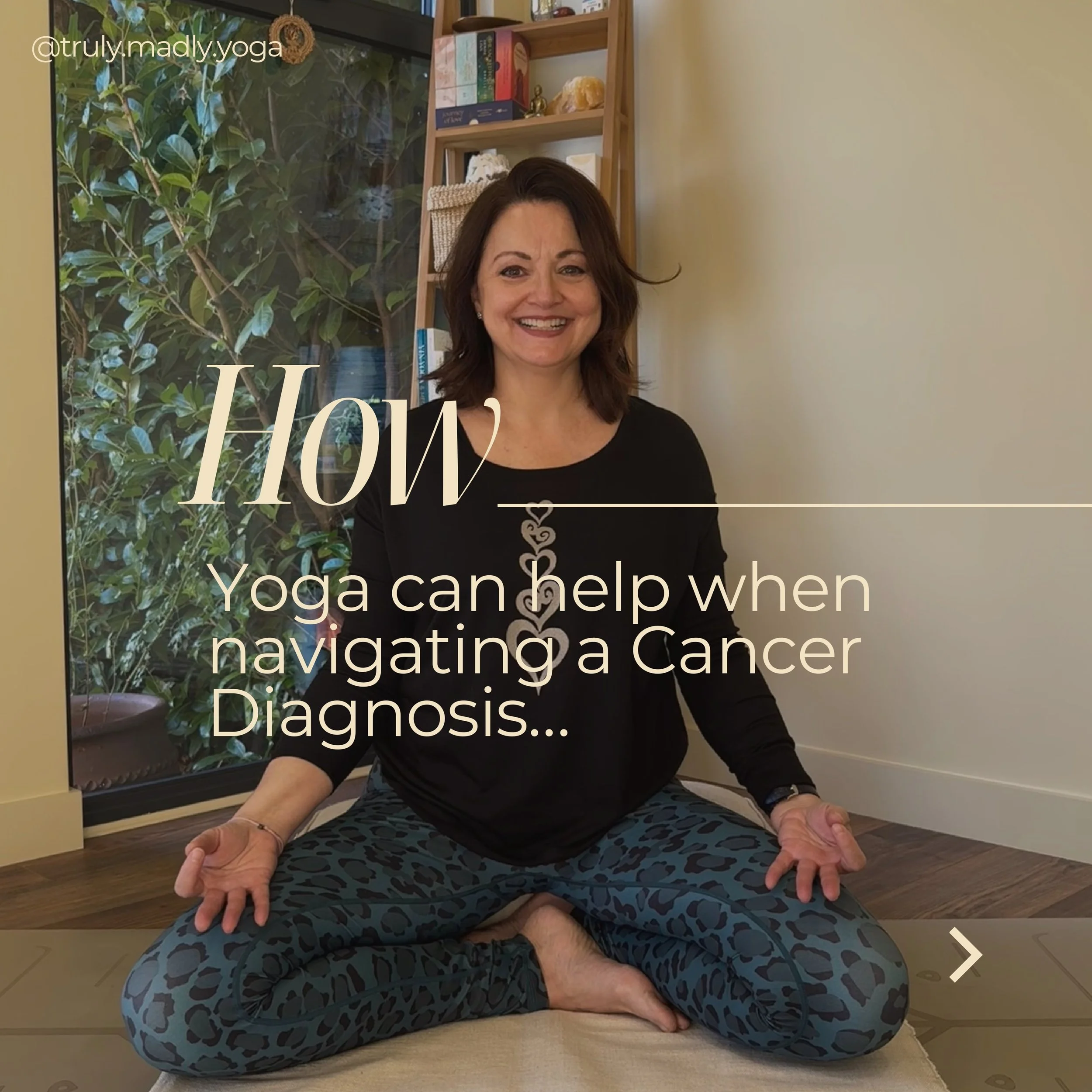 truly.madly.yoga practicing yoga indoors, sitting cross-legged and smiling, with hands resting on knees in a meditative pose. She is wearing patterned leggings and a black top, positioned on a rug.