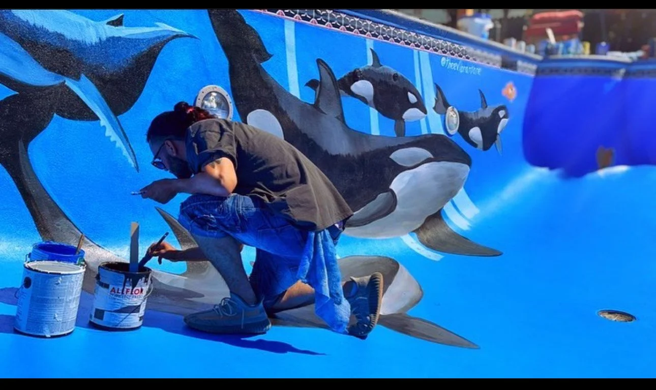 MURALIST PAINTING SHARKS MURAL IN POOL