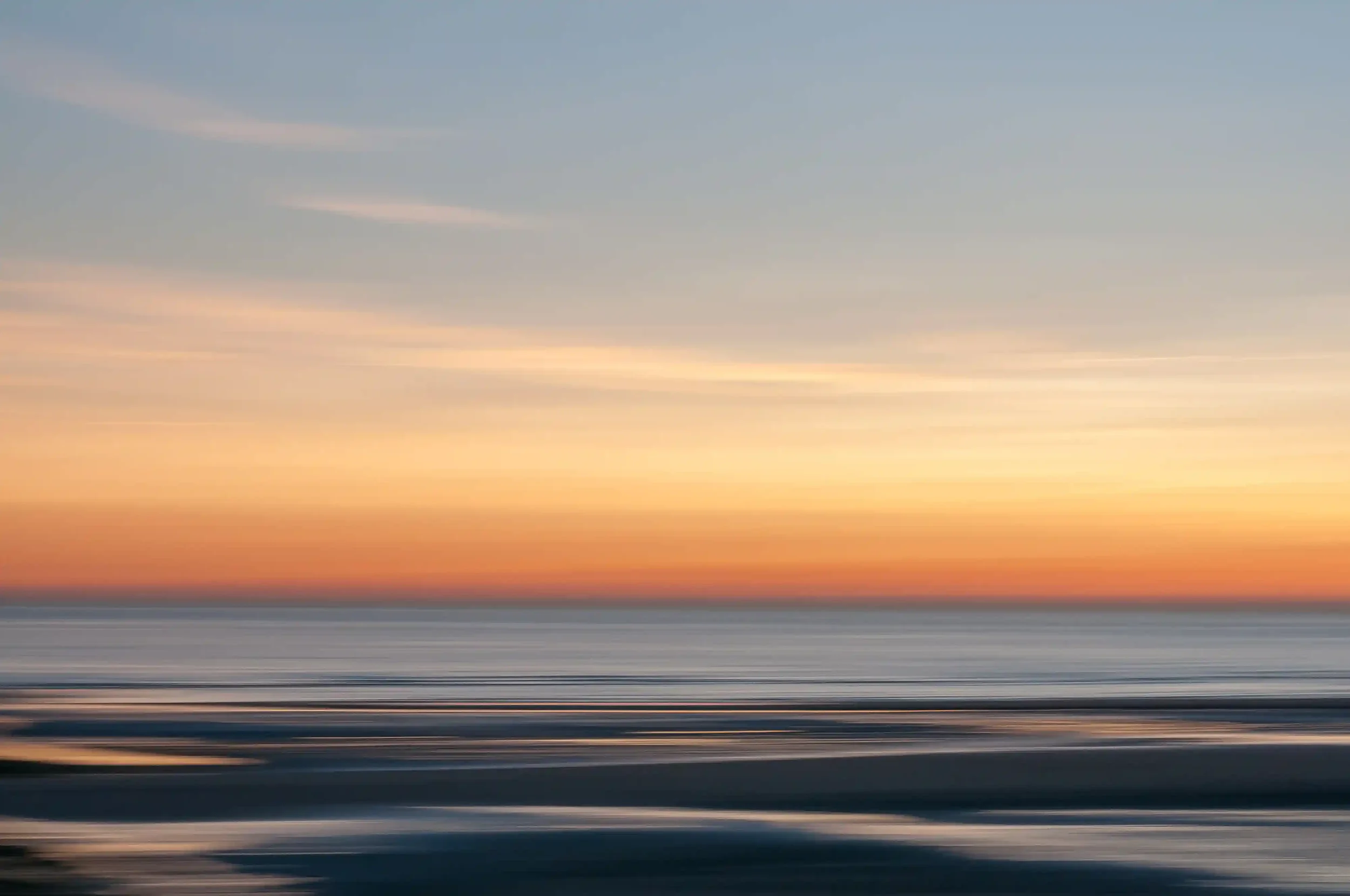 Een foto van een rustige zee bij zonsondergang met een kleurrijke hemel in pastelkleuren en lichtgolven op het water. Gemaakt met ICM techniek. Zonsondergang in Normandie