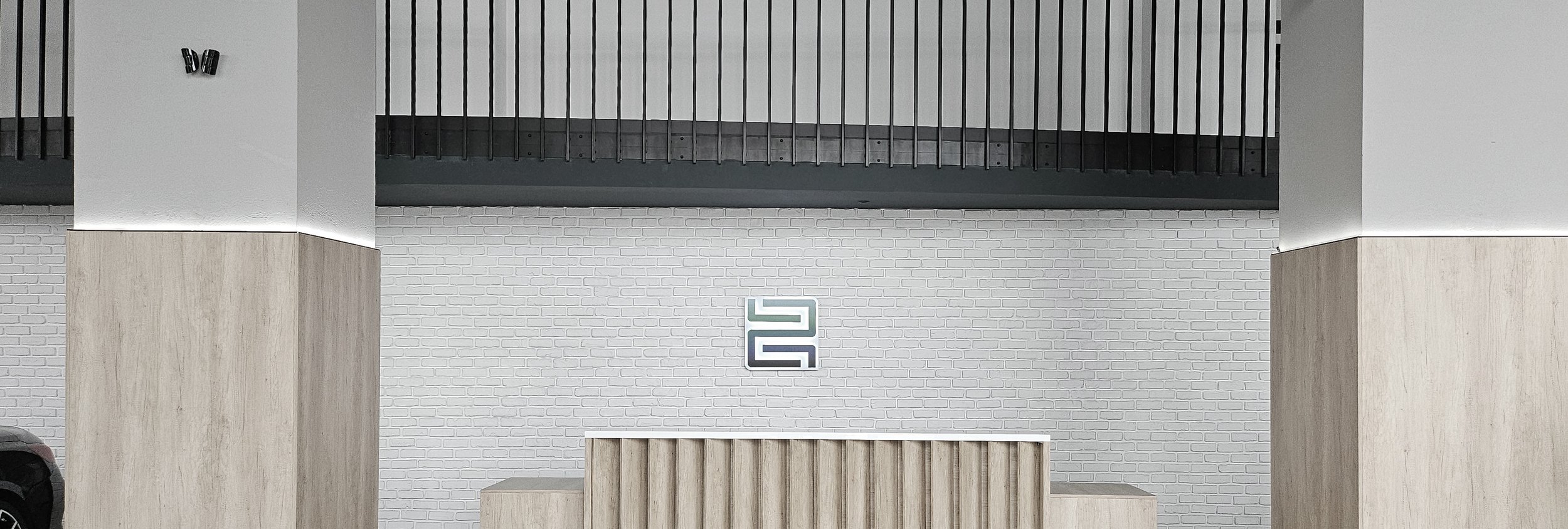 Car showroom interior with a sign made by our graphic design team on a white brick wall. Vedere interioară showroom auto, cu semn creat de echipa noastră pe perete din cărămidă albă