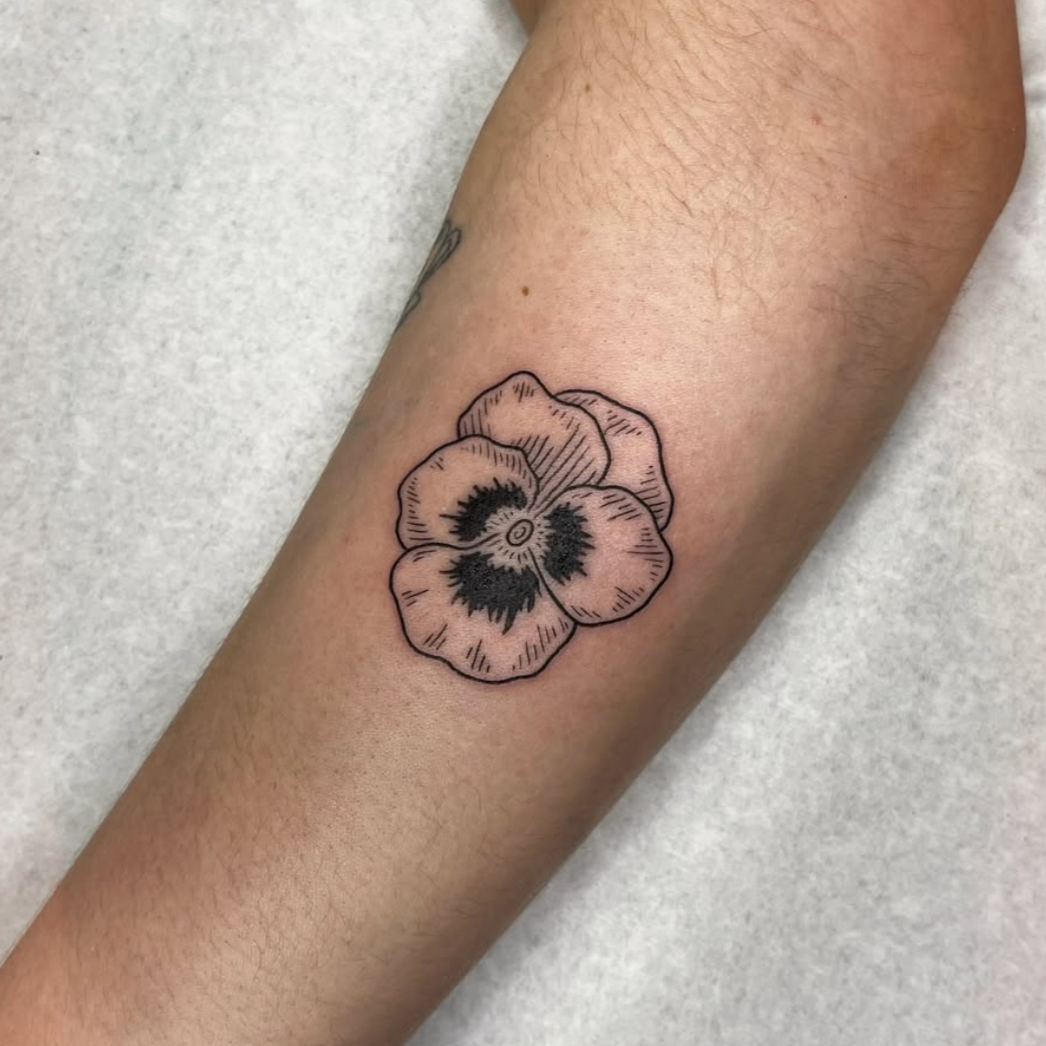 Black outline tattoo of a pansy flower on a person's forearm.