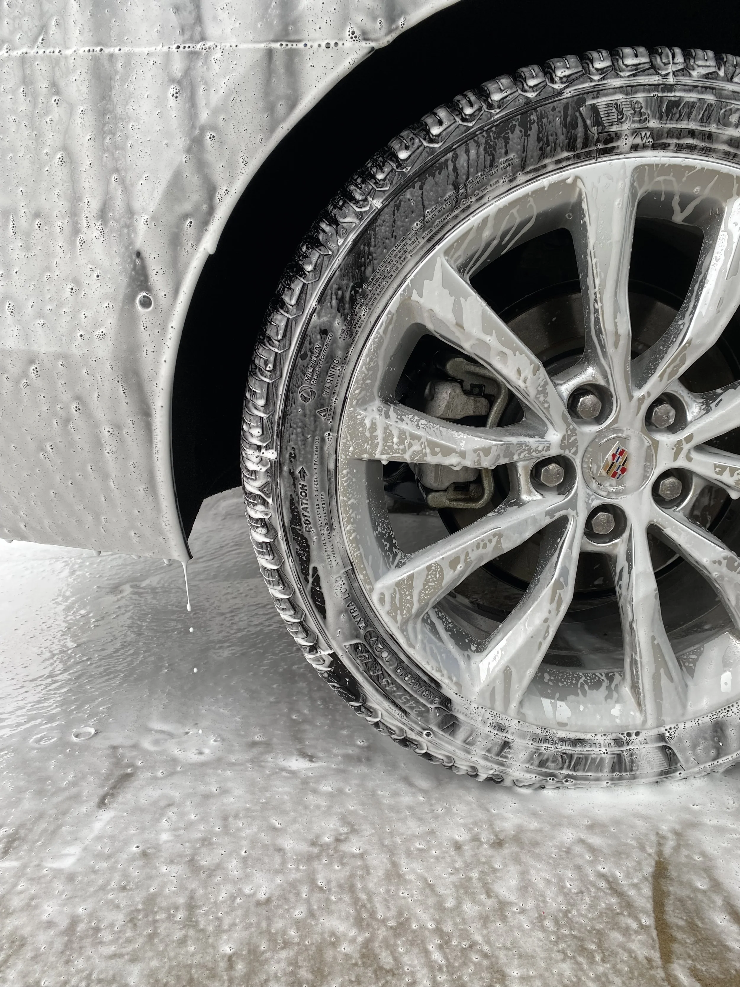 Soapy wheel and tire of a Cadillac, before getting scrubbed