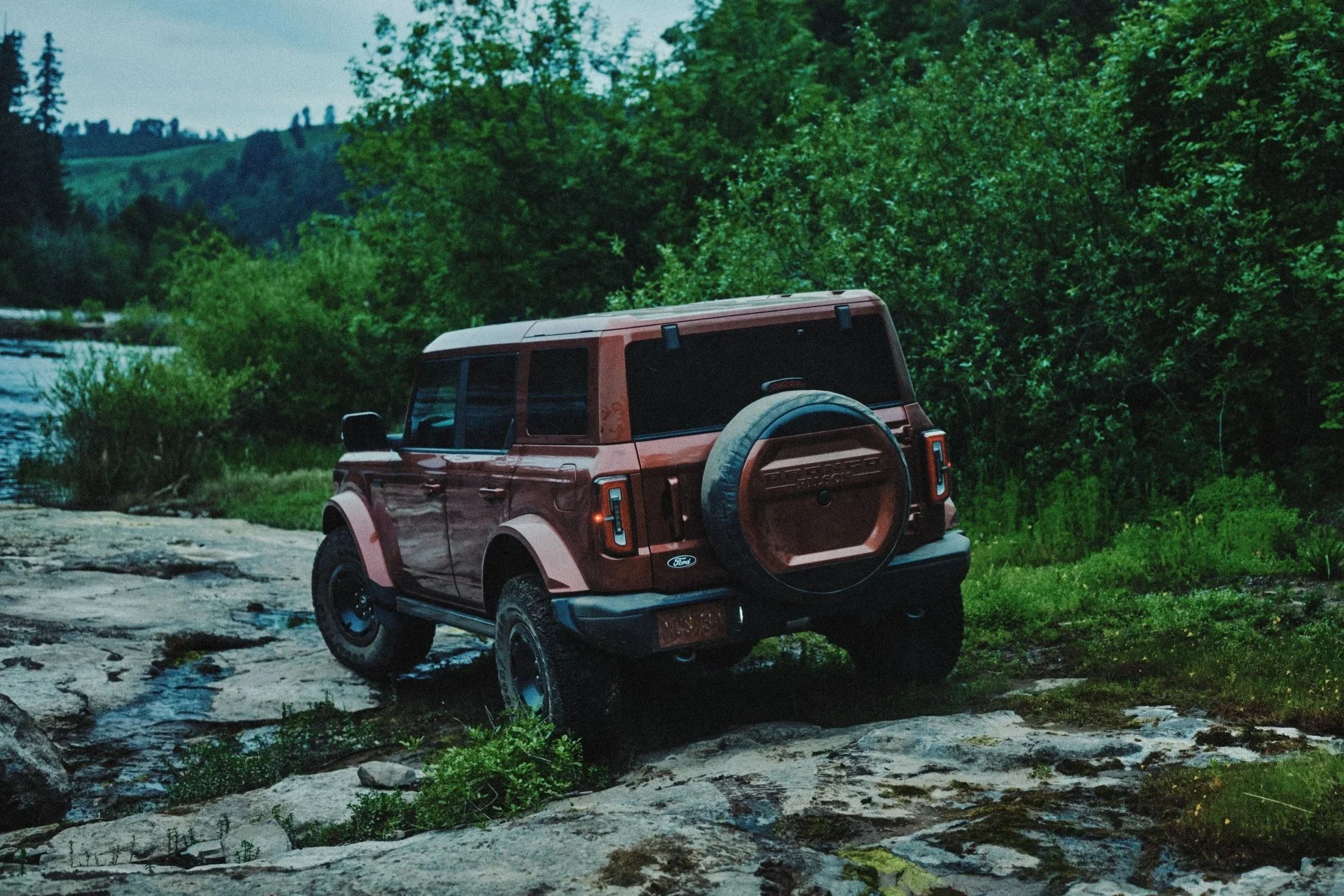 A back view of the 2027 Bronco Filson First Edition overcoming a rocky riverbed