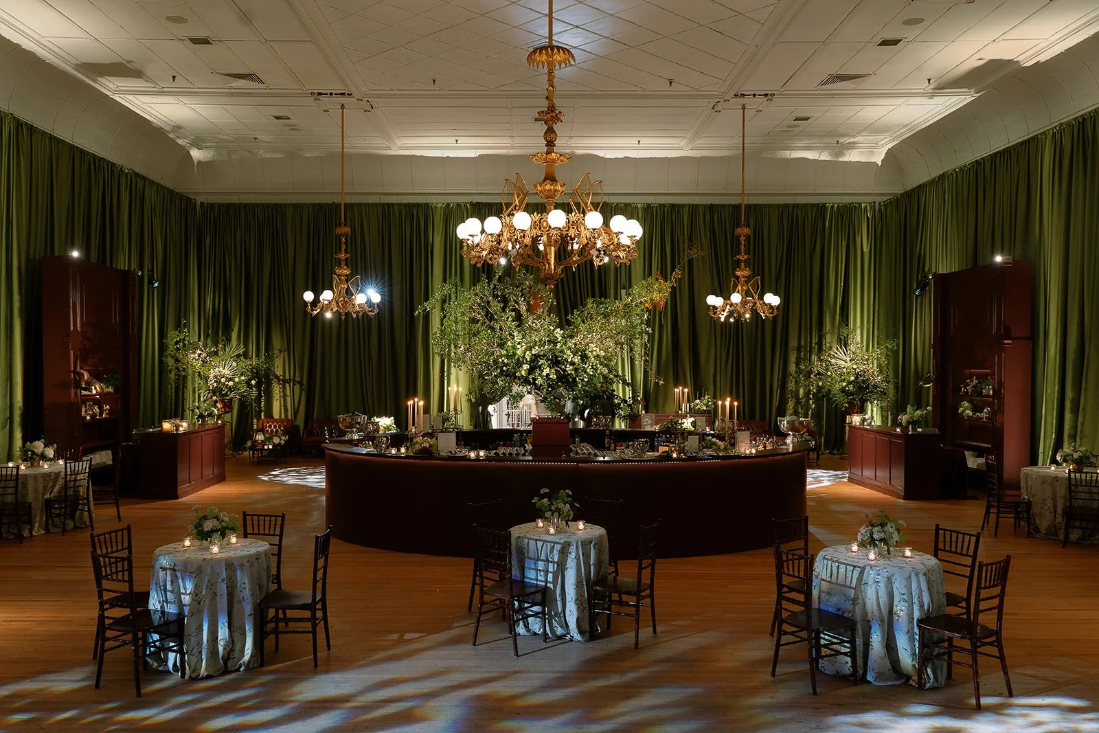 An elegant Charleston wedding reception featuring draped green walls, chandeliers, and an intimate lounge-style layout inside a historic venue.